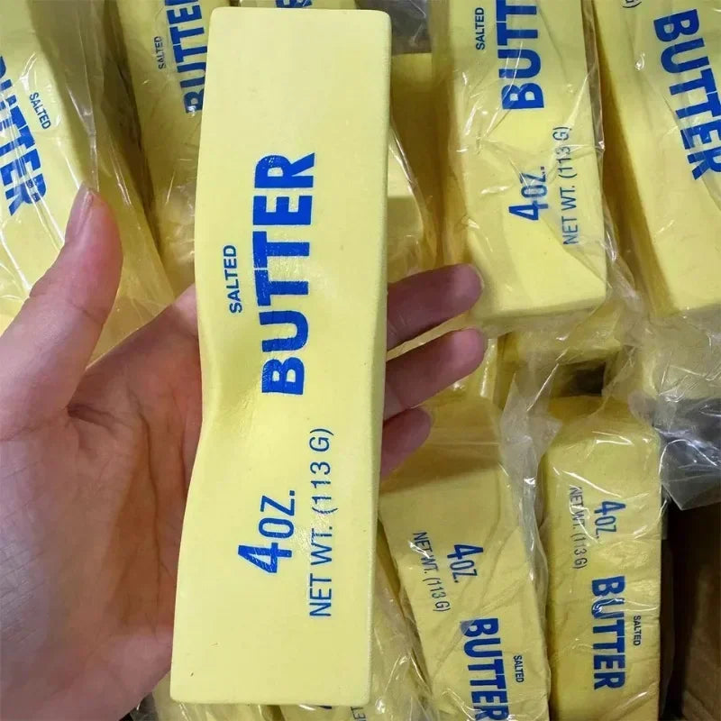 Squishy yellow butter stick fidget toy held in hand with many others in background