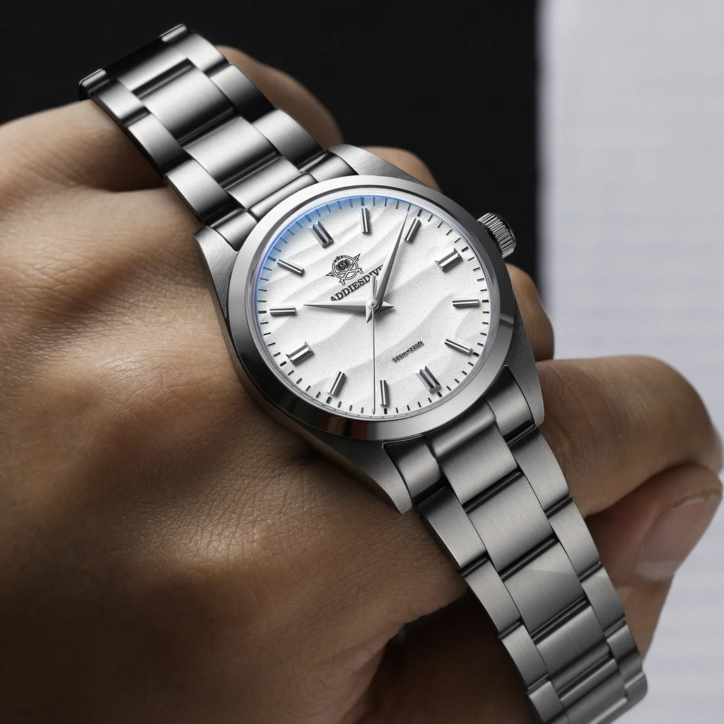 Stainless steel men's watch with a white wave dial held in a hand