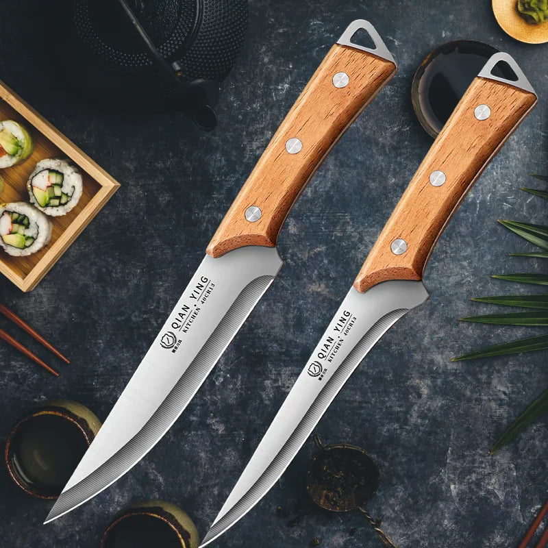 Two stainless steel kitchen knives with wooden handles on a dark background with decorative sushi and cups
