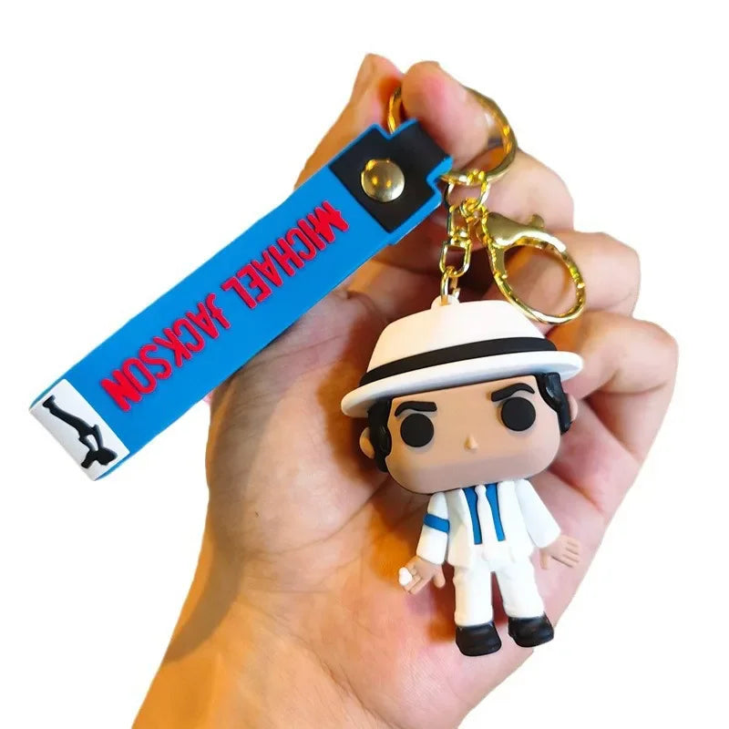 Hand holding a Michael Jackson vinyl-style doll keychain wearing a white suit.