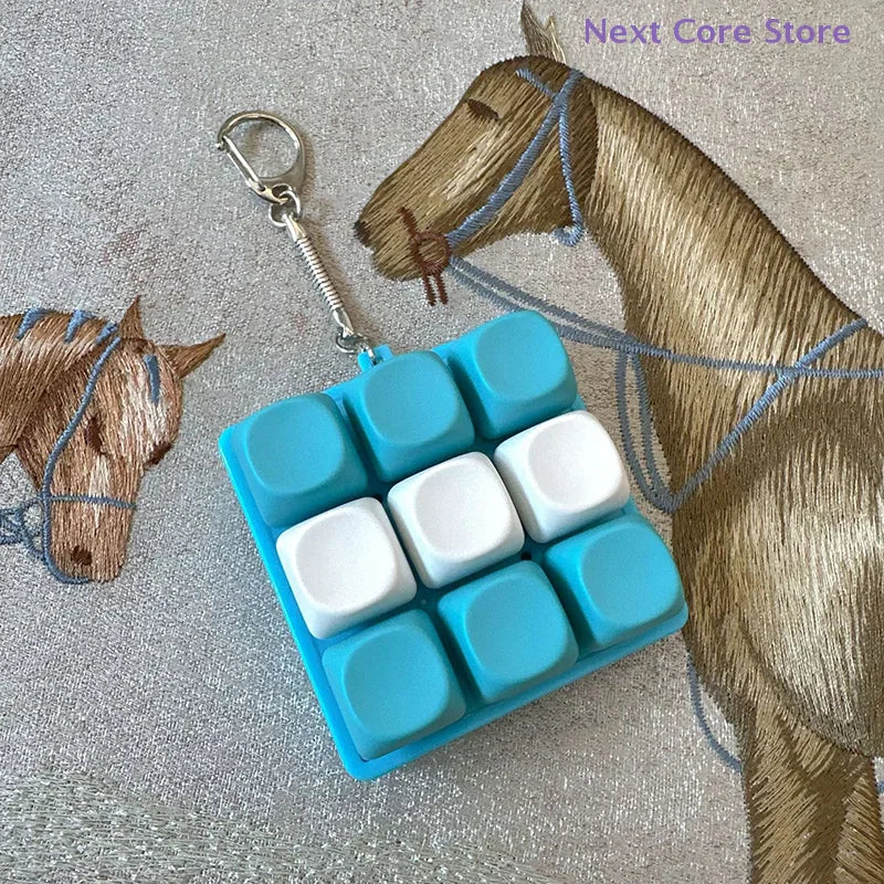A blue and white 9-key keyboard fidget keychain on a fabric with a horse print