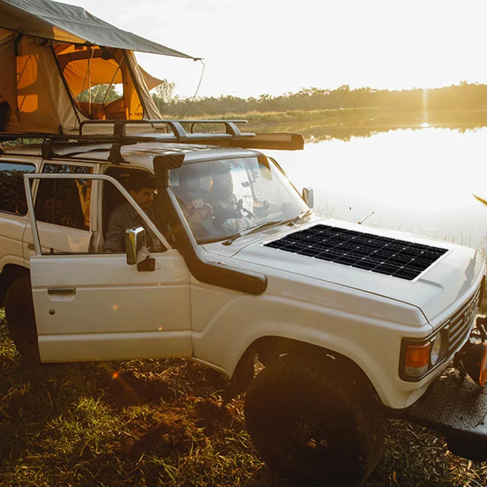 Flexible solar panel mounted on the hood of an off-road vehicle during camping trip