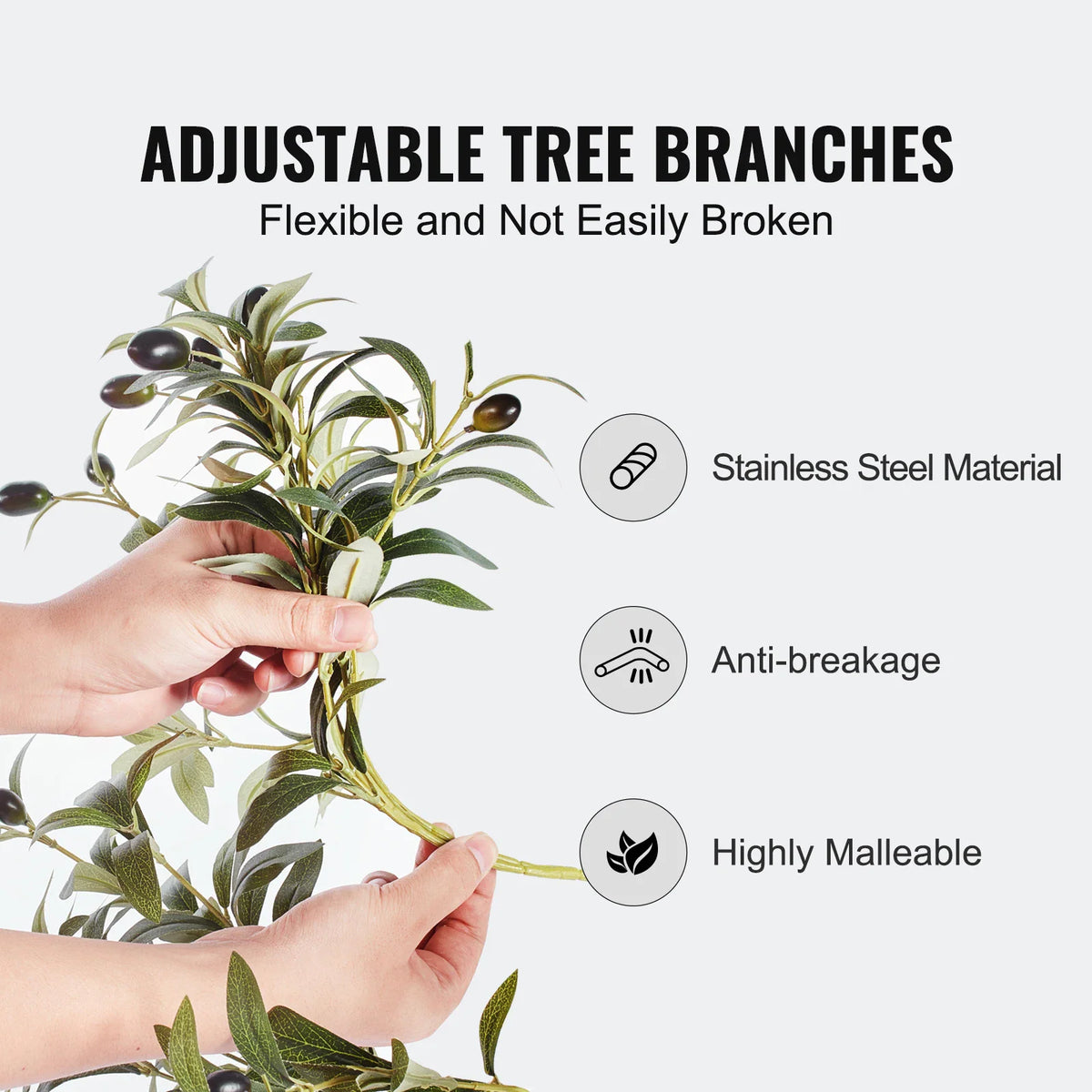Hands bending the branches of an artificial olive tree to show its flexibility and wire material.