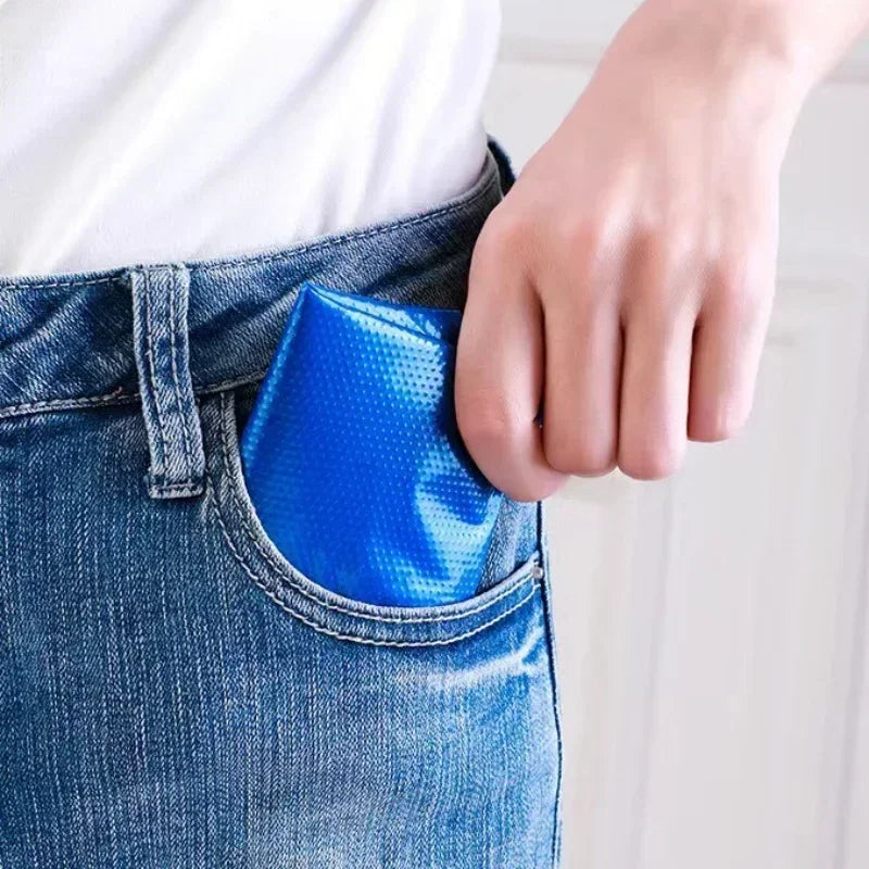 A folded blue plastic shoe cover held in a jeans pocket