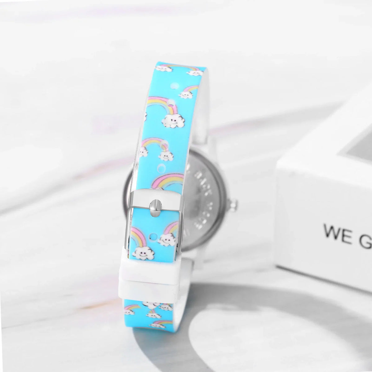 Back view of a blue children's watch with rainbow and cloud print on the silicone strap