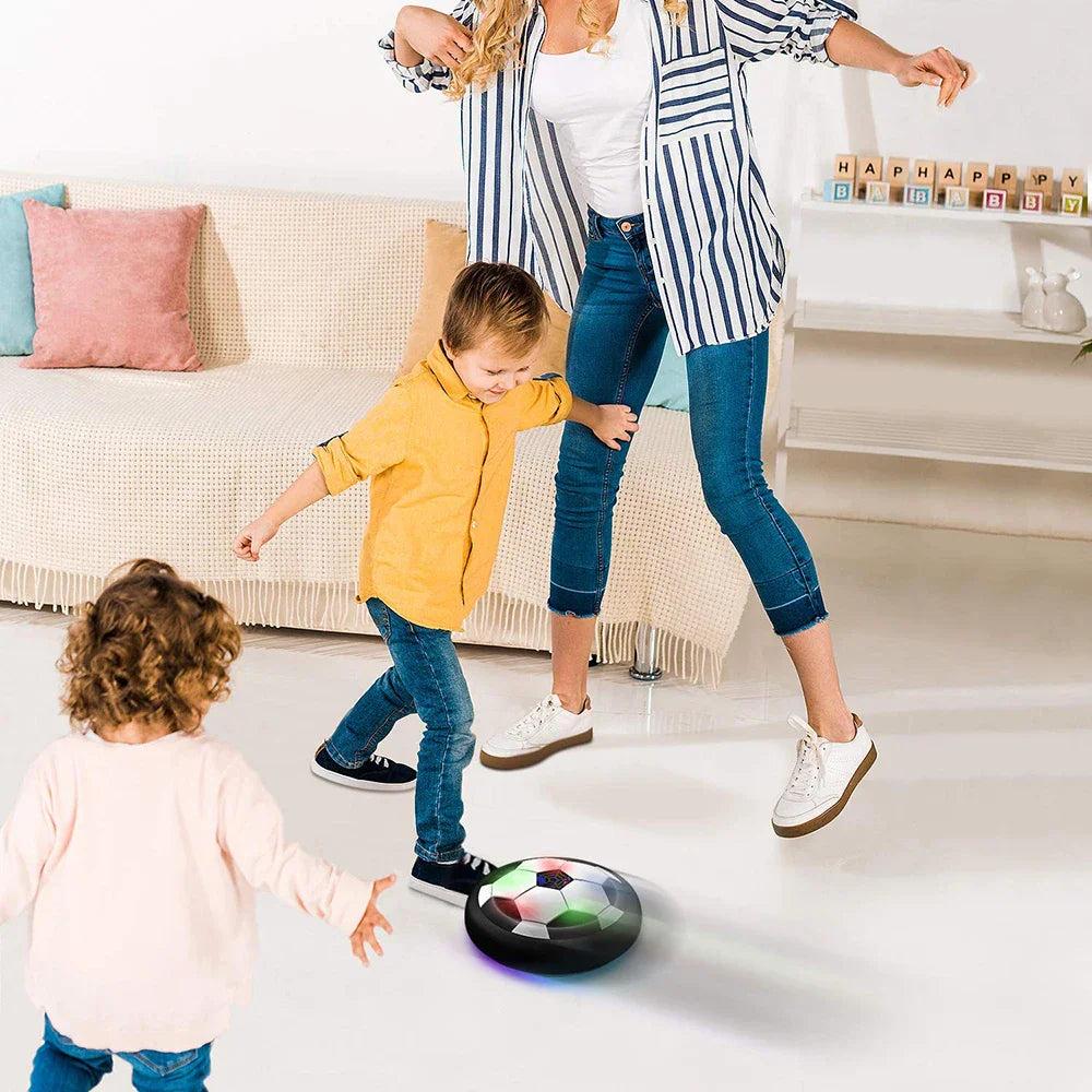 Family playing with an LED hover soccer ball on a bright living room floor