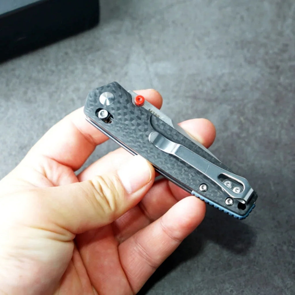 Folding knife with a carbon fiber handle and pocket clip, held in hand
