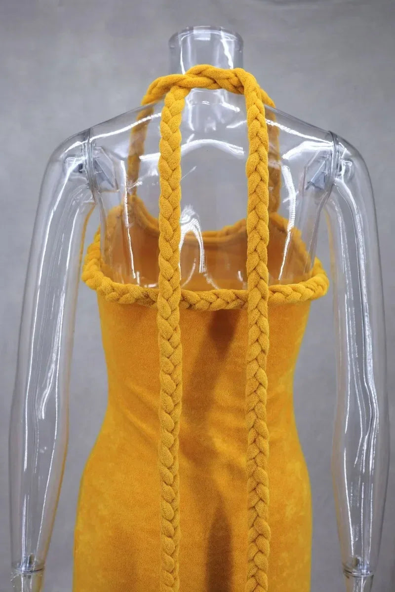 Back view close-up of a mustard yellow velvet halter dress with braided straps on a mannequin.