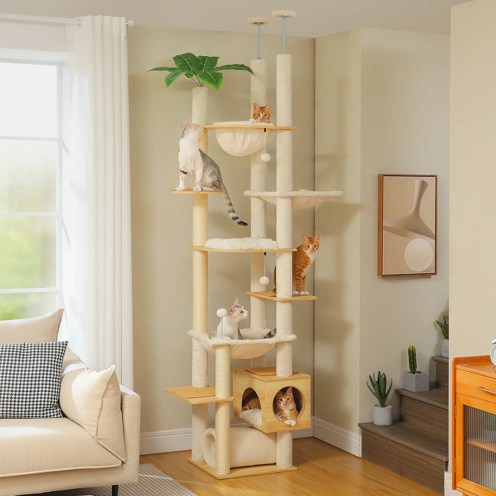 Tall floor-to-ceiling multi-level cat tree with sisal scratching posts, hammock, and condo in a beige room.